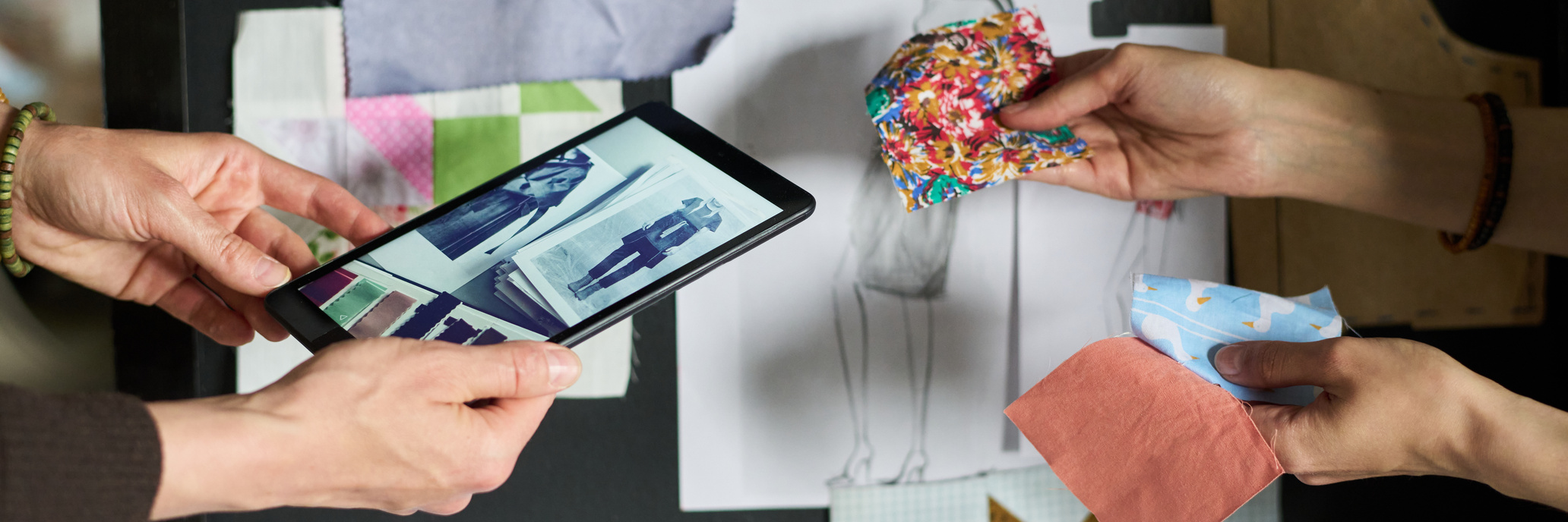 Profissionais analisando tecidos e estampas durante criação de coleção de moda.