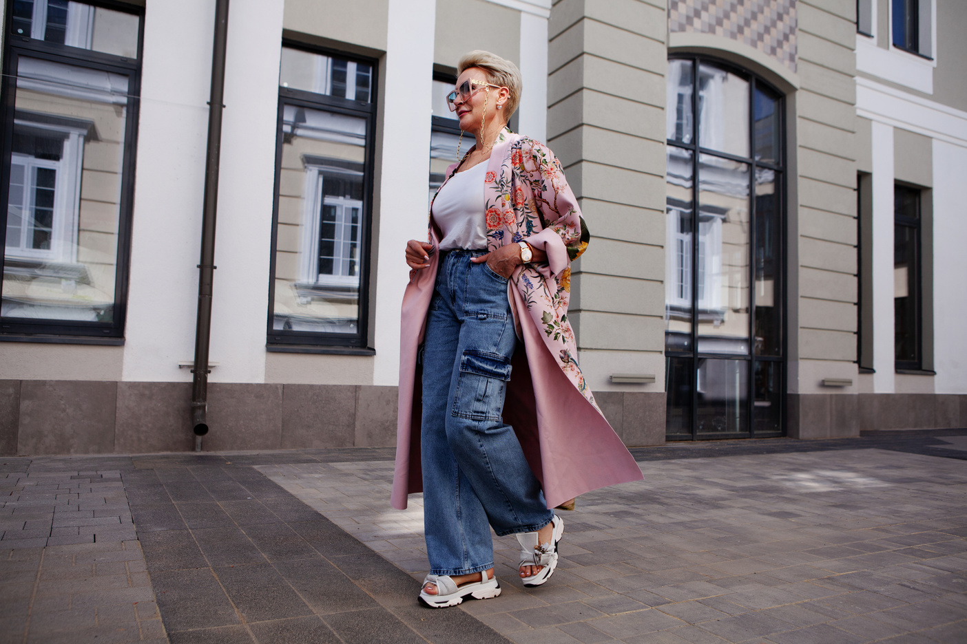 Mulher usando trench coat floral com jeans em look urbano moderno e elegante.